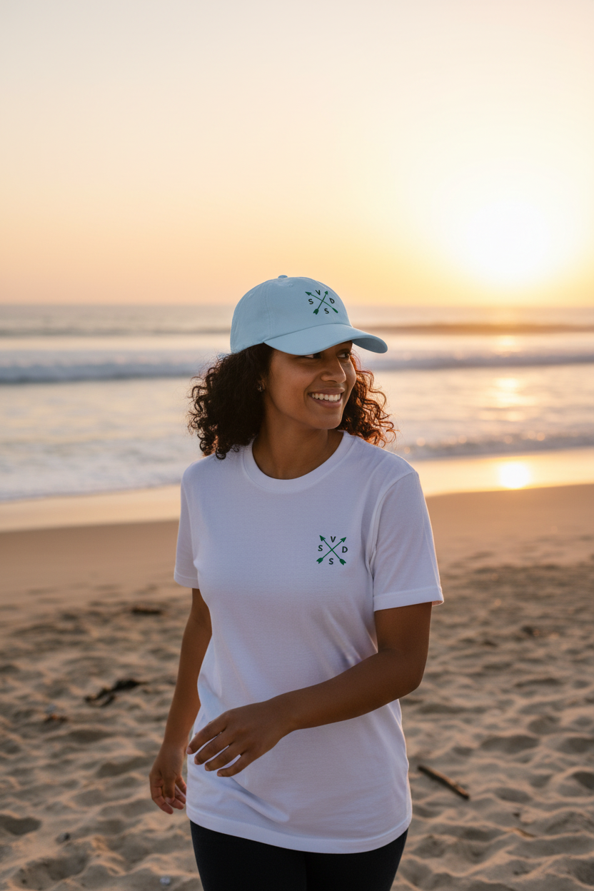 Mujer joven con camiseta logo pequeño SVD y gorra en la playa
